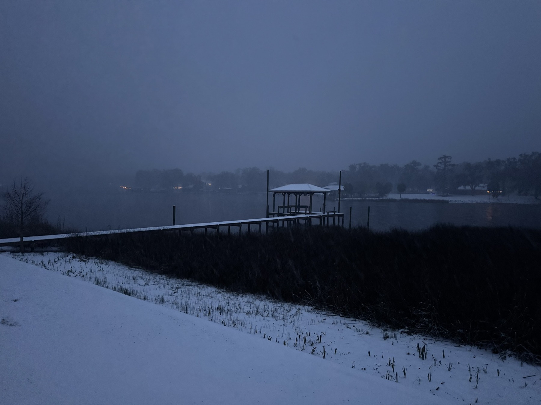 Snow covers the shoreline beneath a dusky blue winter sky
